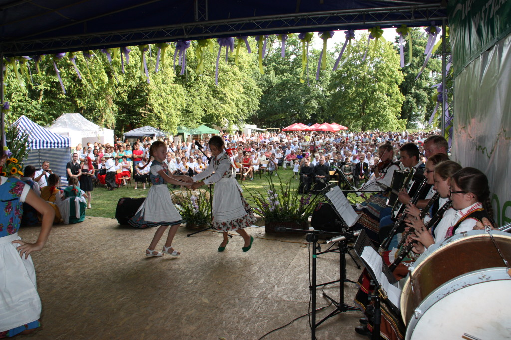 Kapela folklorystyczna i tańczące dziewczynki na scenie podczas lokalnego festynu w Cichowie, w gminie Brudzew