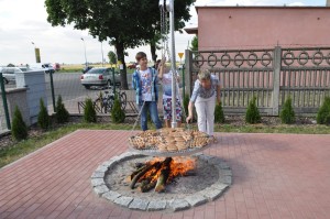 Kiełbaski na ruszcie na podwieszanym nad ogniem grillu w Smulsku, w gminie Przykona