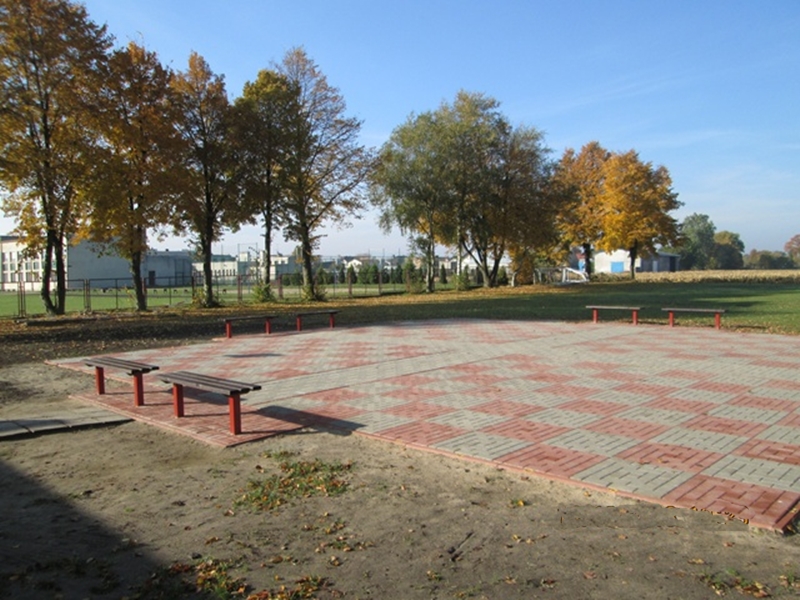 Utwardzony teren dwukolorową kostką brukową tworzącą planszę do gry w szachy w Marzeninie, w gminie Września